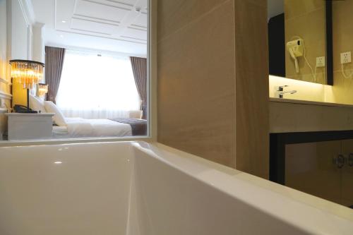 a bath tub in a bathroom with a mirror at Dai Viet Hotel in Thanh Hóa