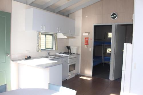 a white kitchen with a sink and a stove at The Lakes Beachfront Holiday Park in Lakes Entrance