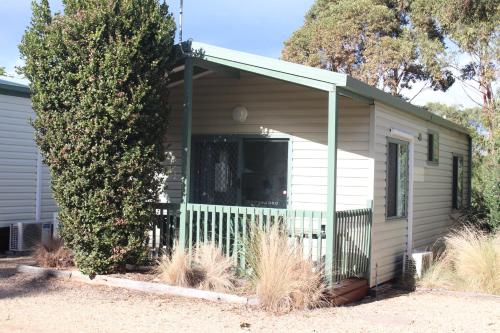 a small white house with a tree in front of it at The Lakes Beachfront Holiday Park in Lakes Entrance
