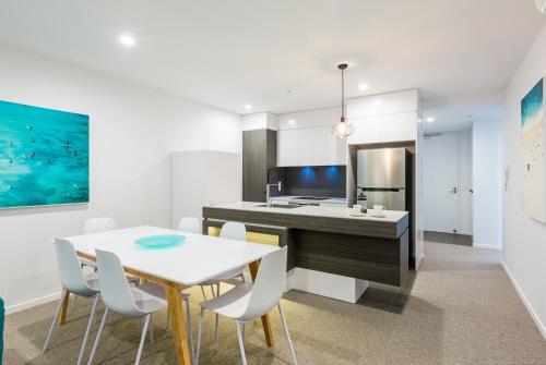 a kitchen and dining room with a table and chairs at Boardwalk Burleigh Beach - Official in Gold Coast
