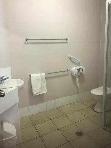 
a bathroom with a toilet, sink, and shower stall at The Bakehouse Motel in Goulburn
