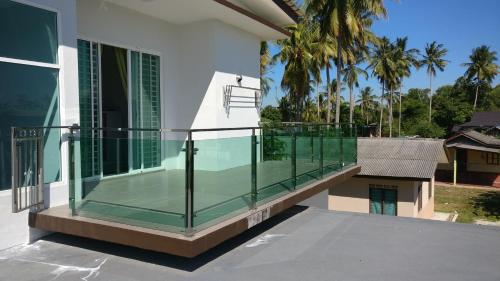 a balcony with glass railing on a house at Villa DSelasih Homestay @UMT UNISZA in Kuala Terengganu