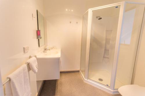 a white bathroom with a shower and a sink at Nelson City TOP 10 Holiday Park in Nelson