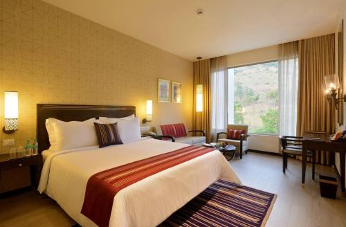 a hotel room with a bed and a large window at Marasa Sarovar Premiere in Tirupati