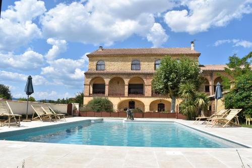 a villa with a swimming pool in front of a building at Mas d'Asvin & Spa in Saint-Christol-lès-Alès