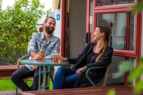 a man and a woman sitting at a table with drinks at Nelson City TOP 10 Holiday Park in Nelson