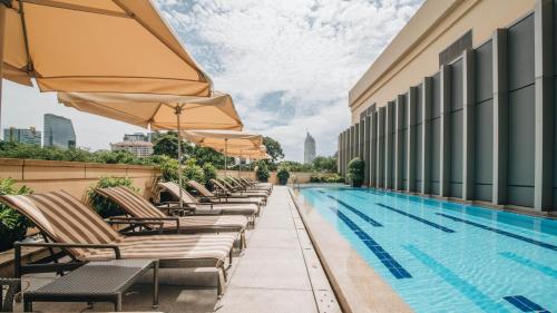 a row of chairs with umbrellas next to a swimming pool at JW Marriott Hotel & Suites Saigon, The Apartments in Ho Chi Minh City