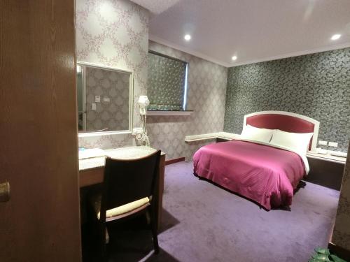 Nice Hotel في تايبيه: غرفة نوم مع سرير وردي ومكتب ومكتب
