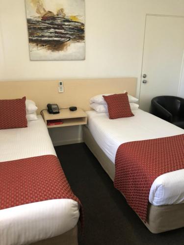a hotel room with two beds with red and white sheets at Adelaide Airport Motel in Adelaide