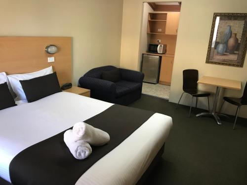 a hotel room with a large bed and a chair at Hideaway Motor Inn in Armidale