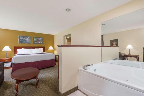 a hotel room with a bed and a bath tub at Days Inn by Wyndham Norton in Norton