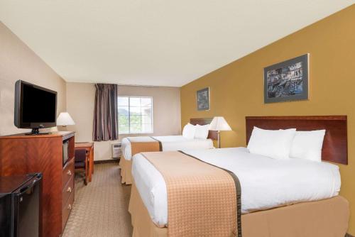 a hotel room with two beds and a flat screen tv at Days Inn by Wyndham Norton in Norton