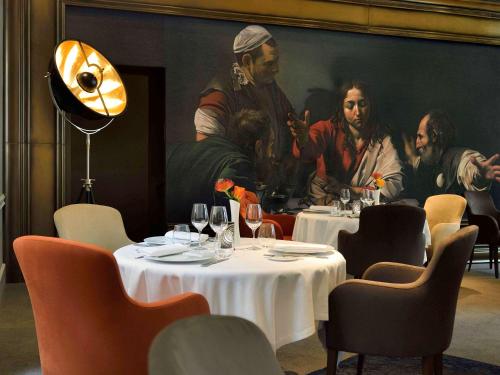 a restaurant with a painting of a group of people at La Cour des Consuls Hotel & Spa Toulouse - MGallery Collection in Toulouse