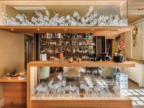 a bar with a display case with glasses at La Cour des Consuls Hotel & Spa Toulouse - MGallery Collection in Toulouse