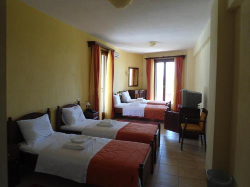 a hotel room with two beds and a television at Villa Belles in Akritochori