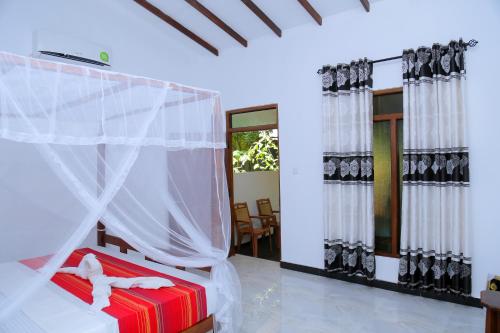 a bedroom with a bed with a mosquito net at Sigiri Mango Garden Eco Resort in Sigiriya