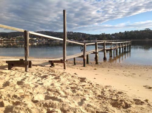 a pier on a beach with a sandy shore at Albacore Apartments in Merimbula