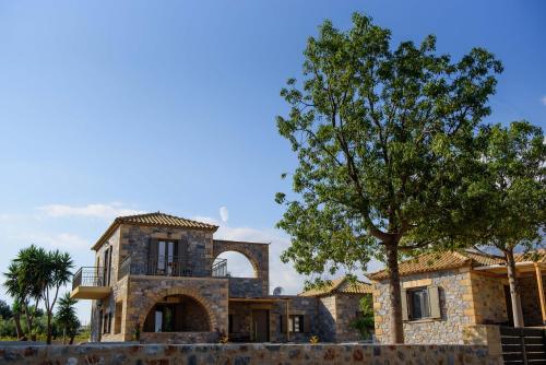 a stone house with a tree in front of it at Calme Suites Mani in Agios Nikolaos