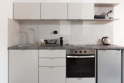 a kitchen with white cabinets and a black oven at Calme Suites Mani in Agios Nikolaos