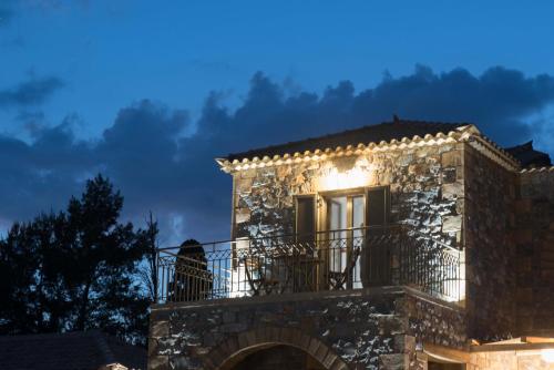 a man sitting on a balcony of a building at night at Calme Suites Mani in Agios Nikolaos