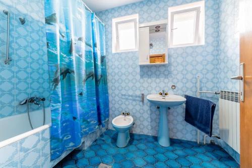 a blue bathroom with a sink and a toilet at Smeštaj Bački Petrovac in Bački Petrovac