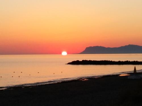 a sunset on the beach with the sun setting over the water at Platanias Aetheras Beach in Plataniás