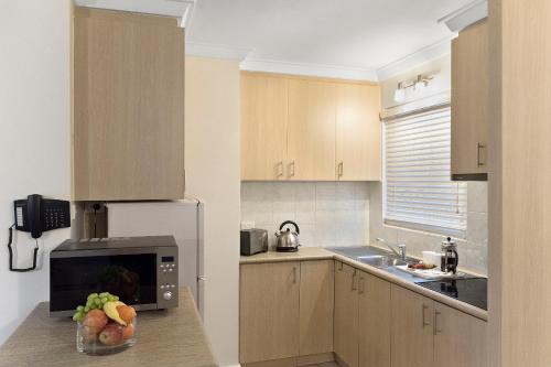 a kitchen with a stove top oven and a microwave at The Peninsula Riverside Serviced Apartments in Perth