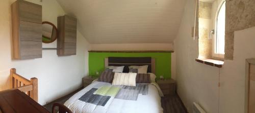 a small bedroom with a bed with a green wall at Gîte Le Cézan in Jégun