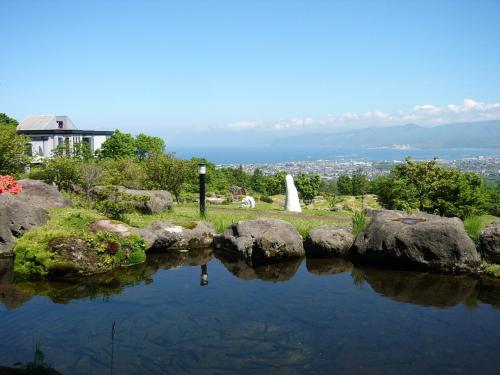 a pond with rocks and a house in the background at Iwanai Kogen Hotel in Iwanai