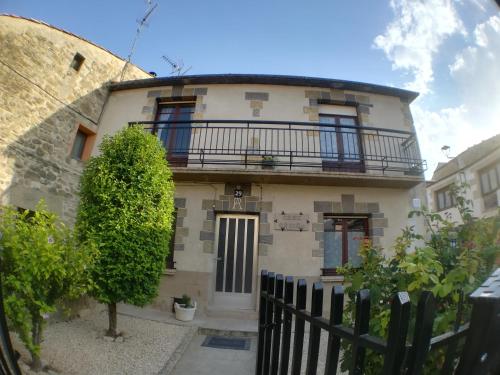a white house with a balcony on top of it at Casa Rural Cariño in Armañanzas