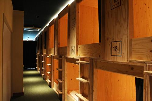 TRAVEL&BOOK HOTEL HULATONCABIN TAKAMATSU في تاكاماتسو: صف من الخزانات الخشبية في الممر