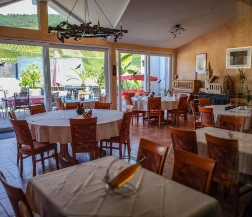 a dining room with tables and chairs and windows at Weinhaus Burg-Schneider in Reil