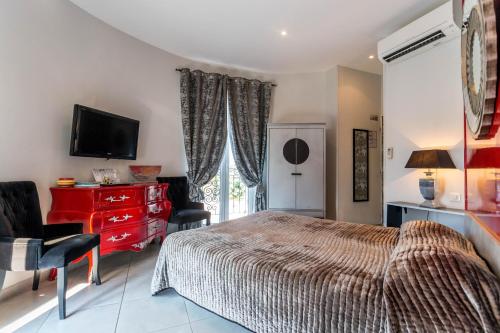 a bedroom with a bed and a dresser and a television at Hotel Villa Des Anges in Grimaud