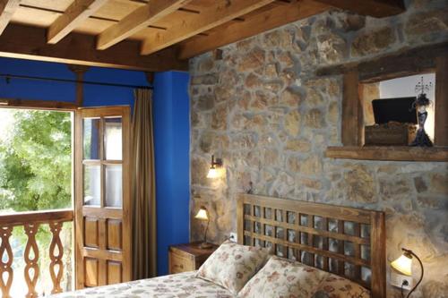 a bedroom with a bed and a stone wall at La Prida Apartamentos Rurales in Caleao