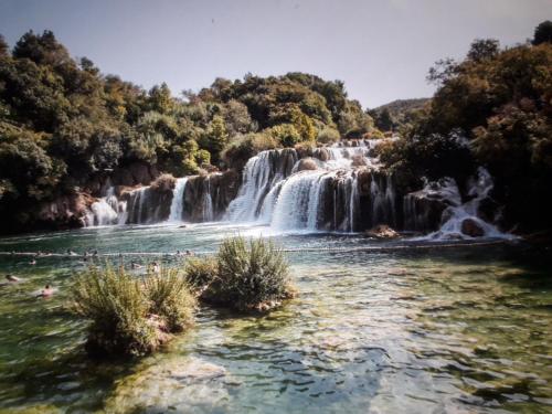 a waterfall with people in the water in front of it at Apartment Karla SNB in Lozovac