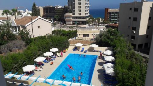 an overhead view of a swimming pool with people in chairs and umbrellas at Polyxeni Hotel Apartments in Limassol