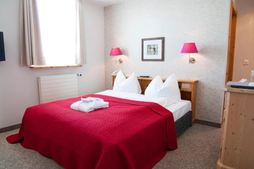a hotel room with a red bed with towels on it at Hotel Rosatsch in Pontresina