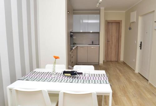 a white dining room table with white chairs and a kitchen at Apartman Bradasevic Tivat in Tivat