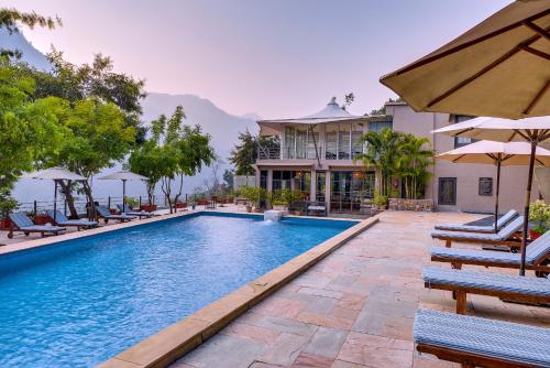 リシケーシュにあるAtali Ganga Resort, Rishikeshの家の前のプール(椅子、パラソル付)