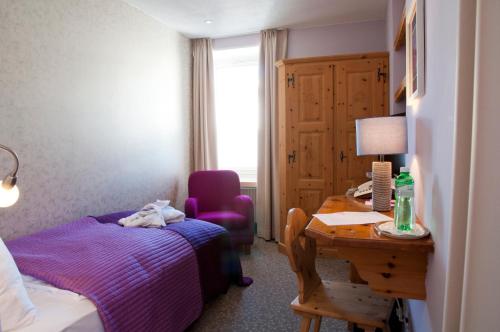 a bedroom with a bed and a desk with a desk at Hotel Rosatsch in Pontresina