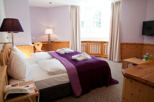 a bedroom with a bed with a purple blanket at Hotel Rosatsch in Pontresina