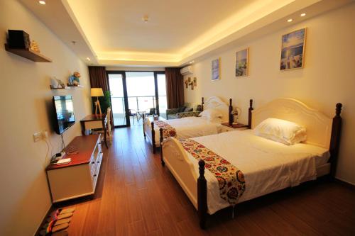 a hotel room with two beds and a desk at Coast-Inn Hailing Island in Yangjiang