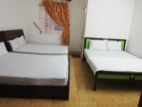 two beds in a room with a window at Ngoc Phung Guesthouse in Vung Tau