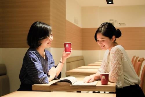two women sitting at a table with cups of coffee at Richmond Hotel Higashi Osaka in Osaka