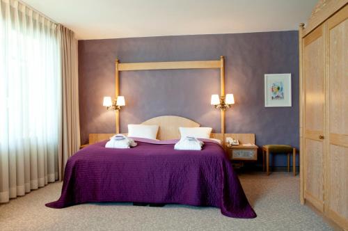 a bedroom with a bed with a purple blanket at Hotel Rosatsch in Pontresina