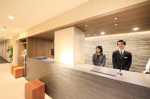 a man and a woman standing at a reception desk at Richmond Hotel Higashi Osaka in Osaka
