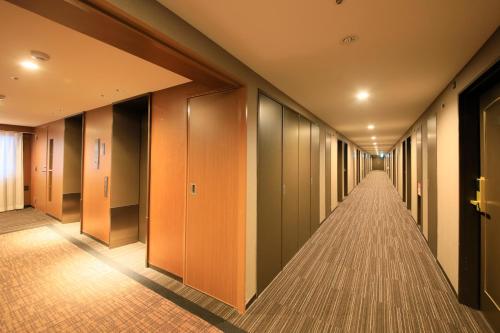 a corridor of a hotel with wooden doors and a long hallway at Richmond Hotel Higashi Osaka in Osaka