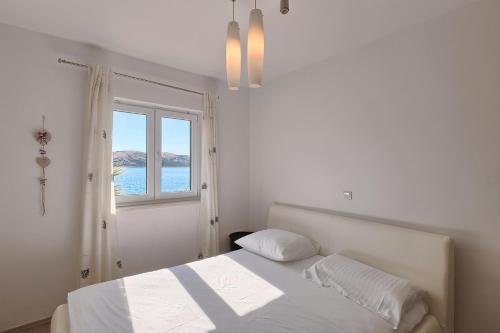 biała sypialnia z łóżkiem i oknem w obiekcie Apartmant Korina w mieście Stara Novalja