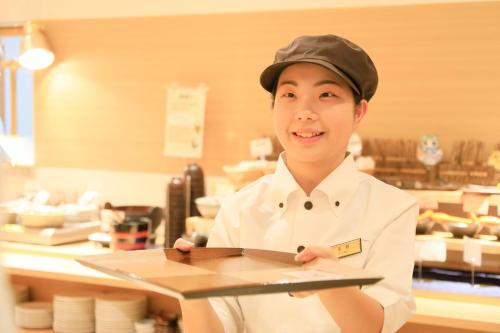 a woman standing in a kitchen holding a tray at Richmond Hotel Higashi Osaka in Osaka