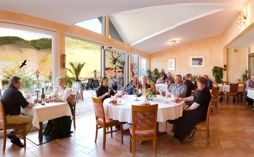 a group of people sitting at tables in a restaurant at Weinhaus Burg-Schneider in Reil